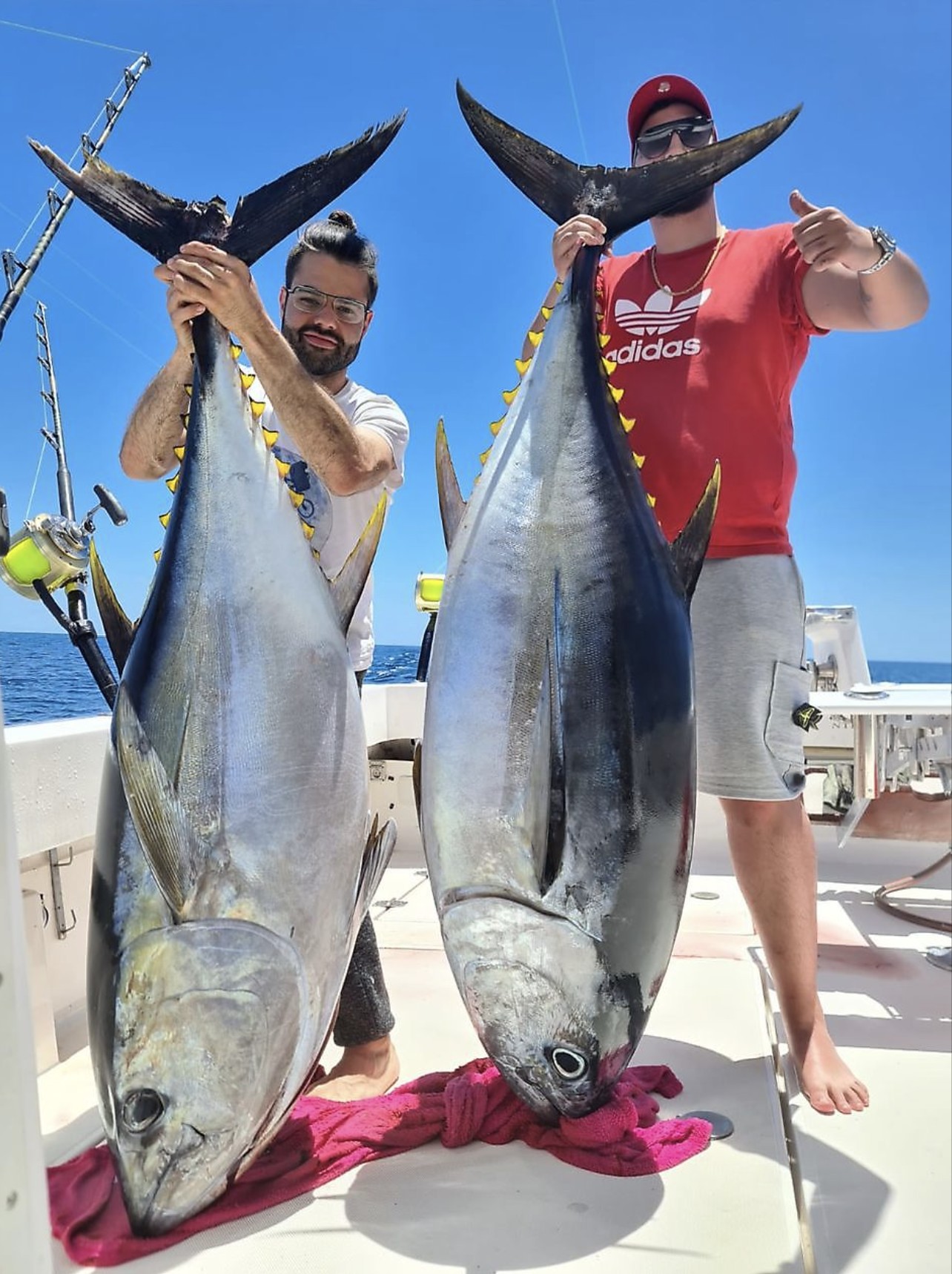 Pair of anglers hoisting two giant yellowfin tuna by the tail